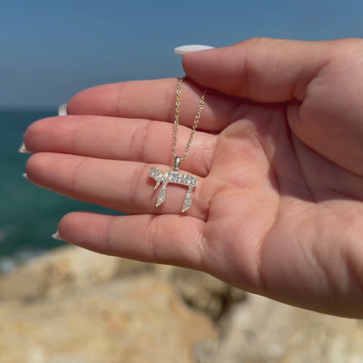 Diamond-set Classic Chai Pendant held against a Mediterranean seaside background