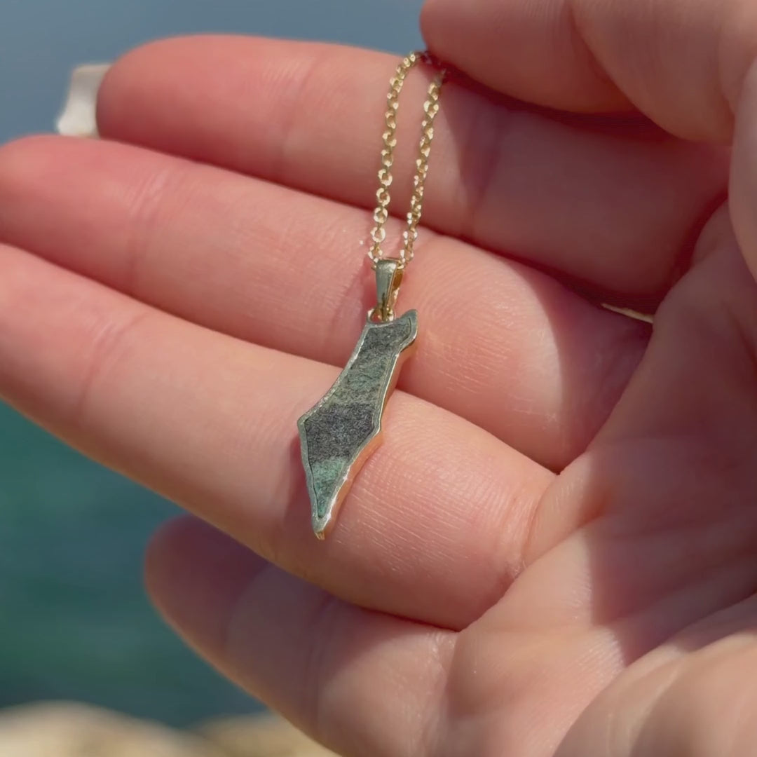 Israel Map Eilat Stone Necklace in yellow gold held against the Mediterranean Sea