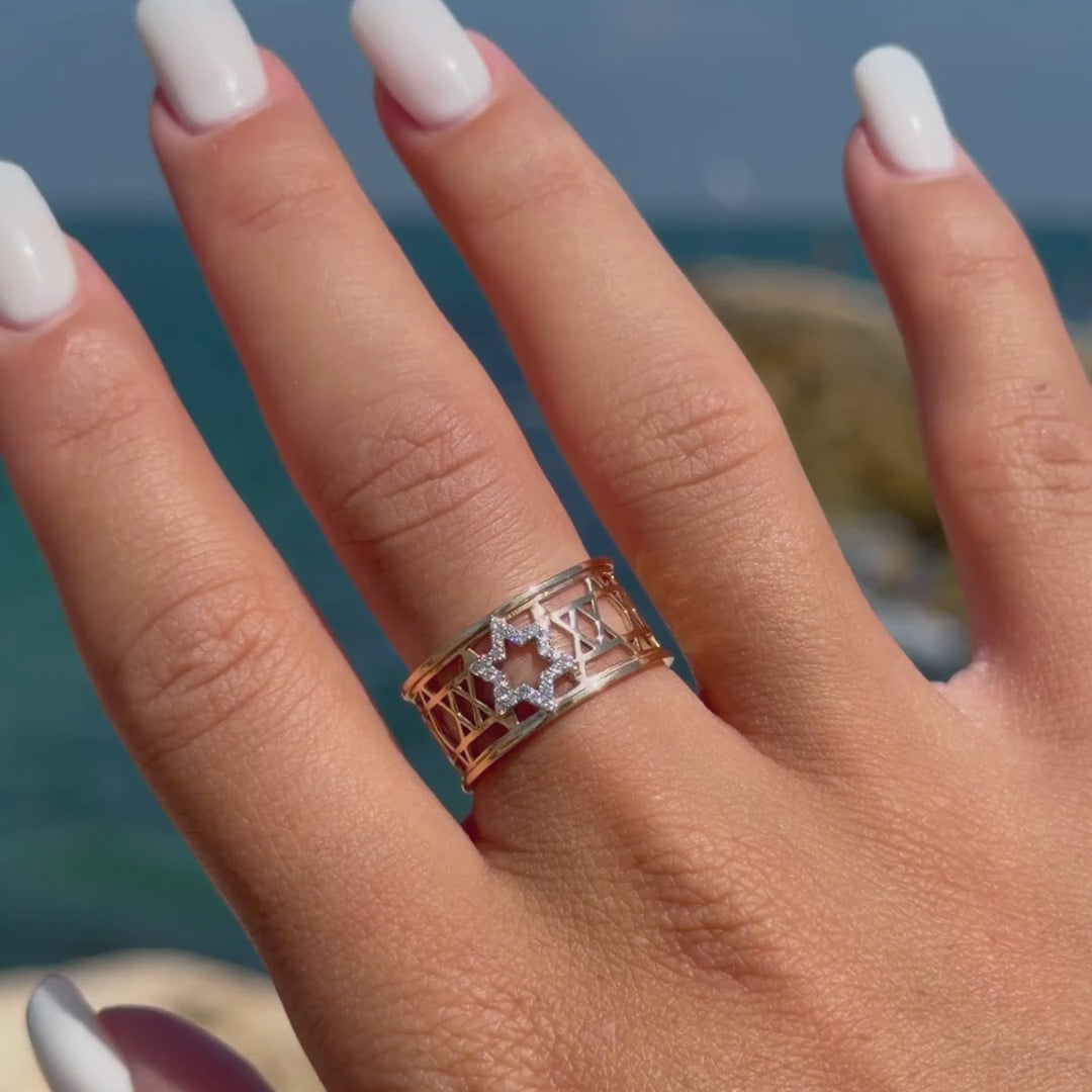 Close-up of the two-tone Star of David Eternal Ring worn against a Mediterranean seaside background